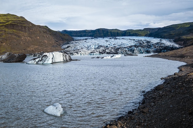 Solheimajokull picturesque glacier in southern Iceland The tongue of this glacier slides from the volcano Katla Beautiful glacial lagoon with blocks of ice and surrounding mountains