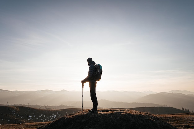 Photo solo hiker on mountain at sunrise with trekking poles