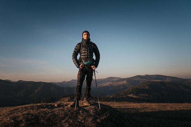 Photo solo hiker on mountain at sunrise with trekking poles