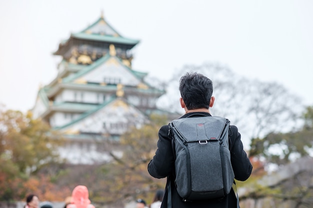 Solo man tourist trveling at Osaka castle in Autumn season, Asian traveler visit in Osaka city, Japan. Vacation, destination and travel concept