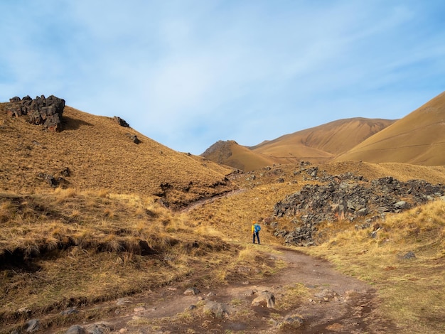 Solo trekking in the Caucasus mountain Man with a backpack is climbing heavily on a mountain trail Adventure solo traveling lifestyle concept active weekend vacation on the wild nature