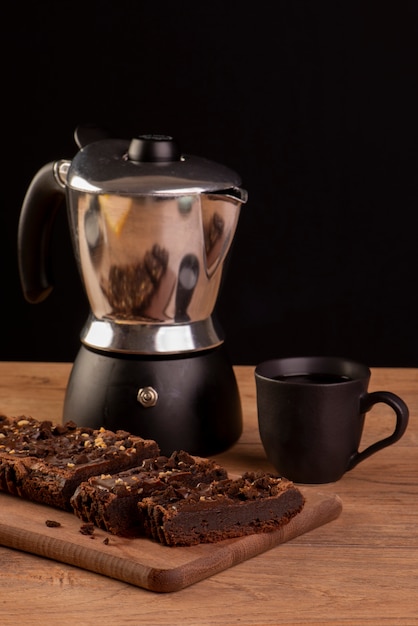 Some brownie slices on wood, a coffee maker and a cup of coffee.