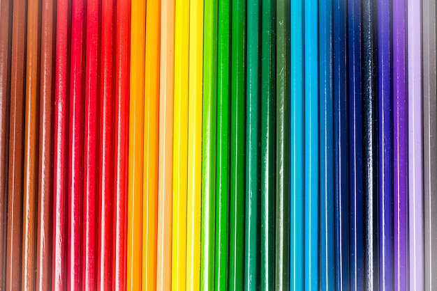 Some different colored wooden pencil crayons placed in a row in front of a white isolated background