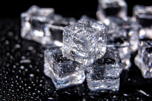 Some ice cubes on glass table. Isolated on black background. Melting ice cubes