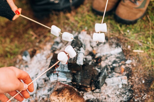 some marshmallows above a burning wood on a field