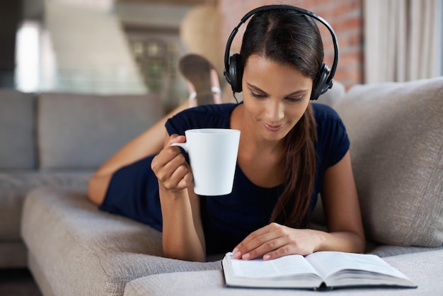 Some of my favourite things Shot of a beautiful young woman relaxing on her couch with music and a good book