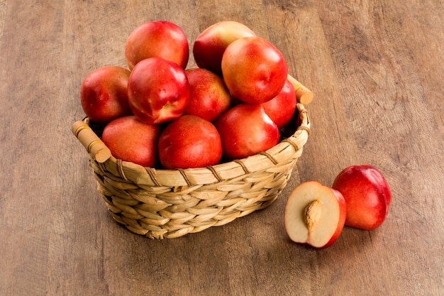 Some peaches in a basket over a wooden surface