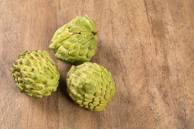 Some Sugar-Apples over a wooden table. Atemóia fruit