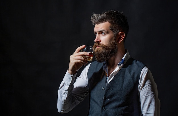 Sommelier tastes expensive drink Degustation tasting Man with beard holds glass of brandy Tasting and degustation concept Bearded businessman in elegant suit with glass of whiskey