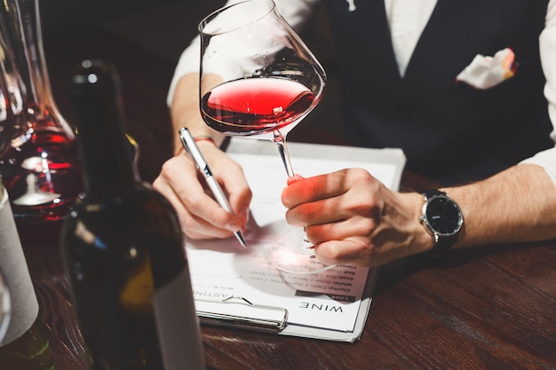 Sommelier writes on clipboard describing red wine at table