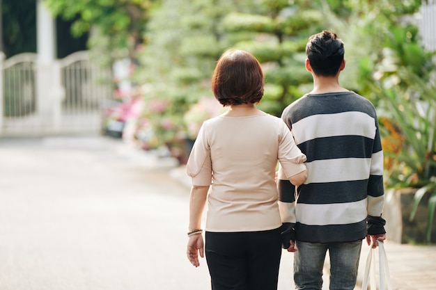 Son helping mother to carry grocery bag