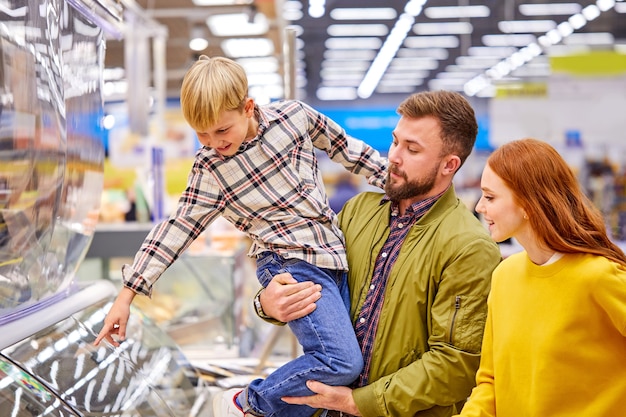 Son show something delicious to parents in store, he wants parents to buy it, point finger