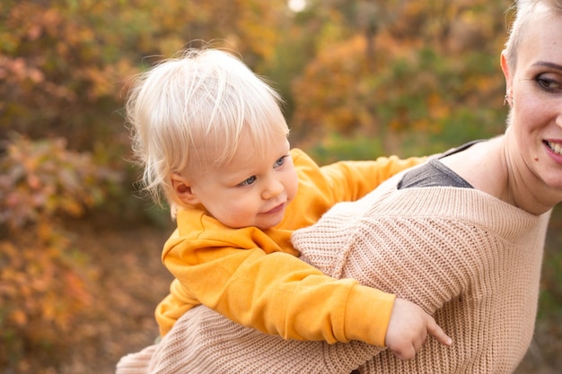 Son with mother in autumn park background with golden trees