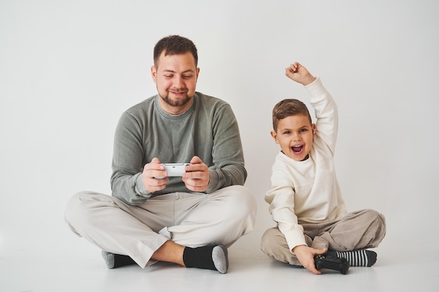 Son won father in game on console Happy child with gamepad raises his hands up and rejoices in the victory in the game