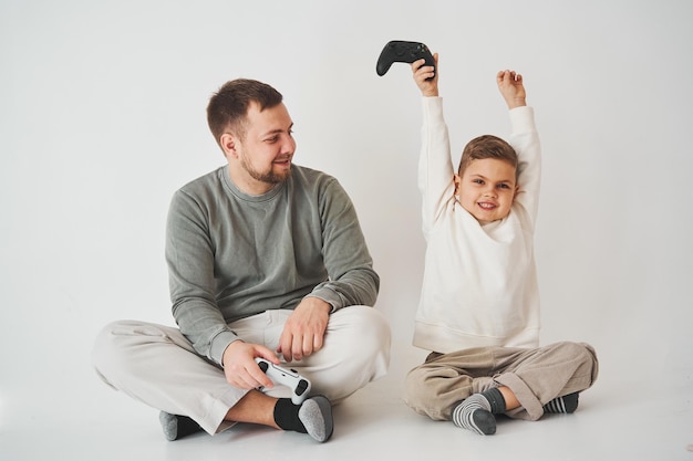 Son won father in game on console Happy child with gamepad raises his hands up and rejoices in the victory in the game