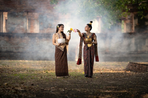 Songkran Festival. The girl in Thai national costume is splashing water on Songkran Day.