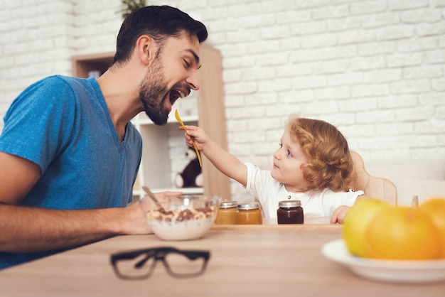 Sons is Feeding His Father a Breakfast at Home.