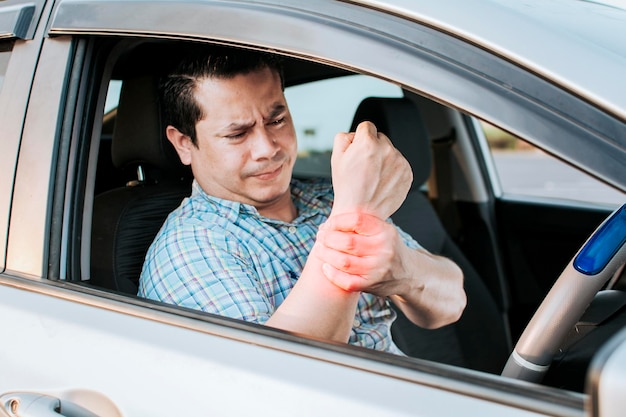 Sore driver man touching his wrist Driver with hand pain Suffering driver at the wheel rubbing his arm from so much driving Sore man tired of driving Driver suffering from wrist pain