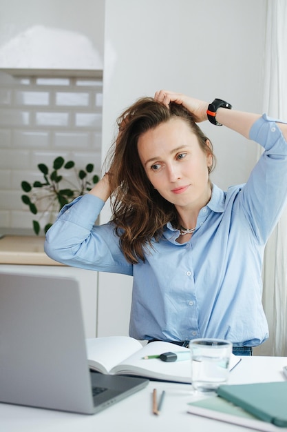 Sore uplifted business woman sitting behid a desk massaging her head