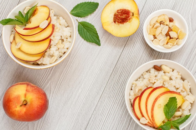 Sorghum porridge with pieces of peach cashew nuts and almond in porcelain bowls fresh peaches