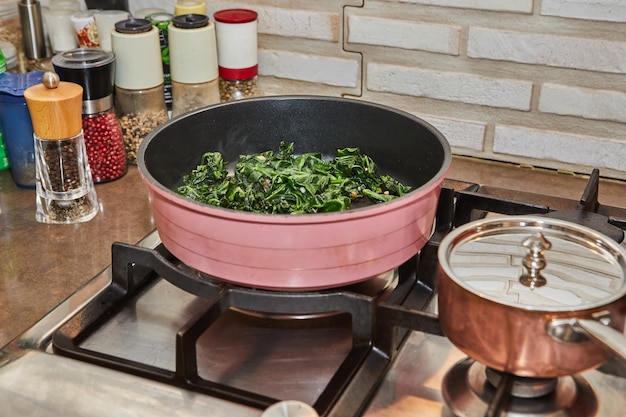 Sorrel is fried in frying pan in oil on gas stove