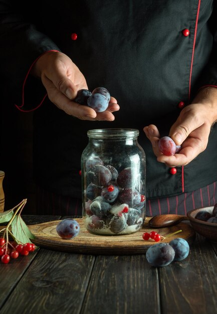 Sorting plums by the cook hands Cooking sweet jam from fresh plum and sugar on the kitchen table