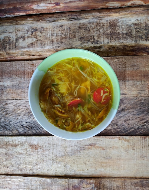 Photo soto kudus. authentic clear chicken soup from kudus on a wooden background, central java, indonesia