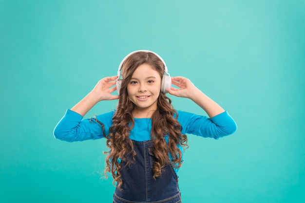 Sound of the childhood Adorable little girl listening to sound track on blue background Cute small child wearing headphones playing electronic sound Relaxing with melodious sound