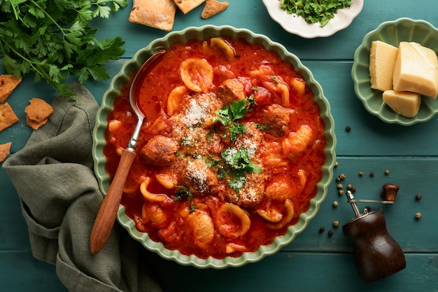 Soup Fresh tomato soup with meatballs pasta vegetables and parsley in green rustic bowl on wooden background Traditional Italian cuisine Healthy dinner eating Top view Autumn cozy dinner concept