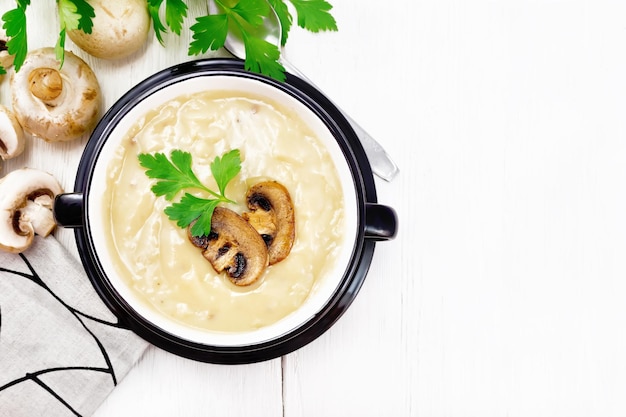 Soup puree of champignon in bowl on light board top