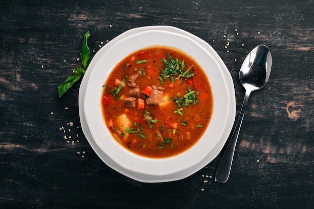 Soup with beef tomatoes and fresh vegetables On a wooden background Top view Copy space