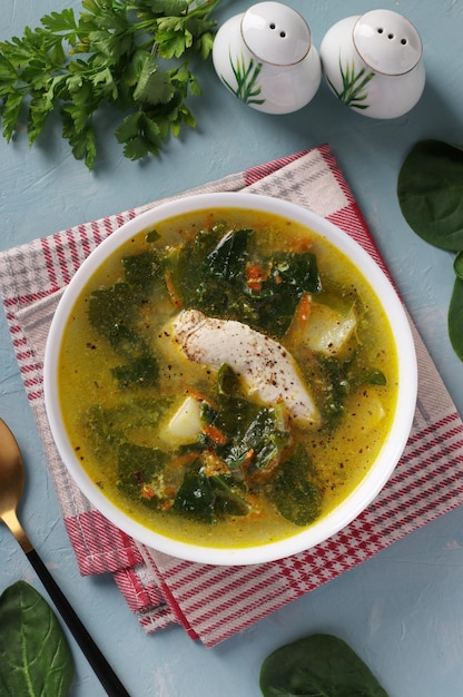 Soup with chicken spinach and egg in white bowl Vertical format