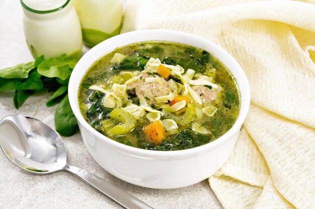 Soup with meatballs and pasta in bowl on stone