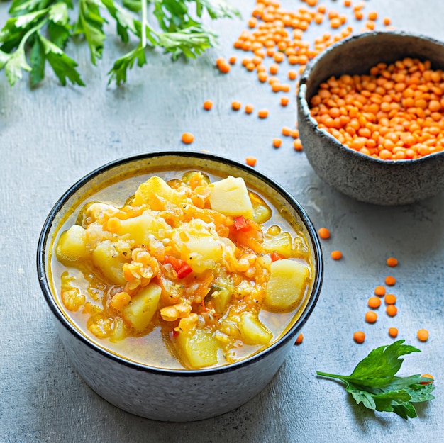 Soup with red lentils and vegetables in a bowl on a blue background.Traditional dish