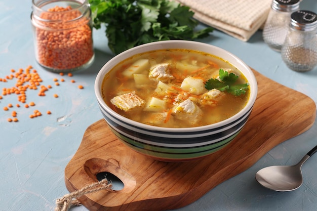 Soup with turkey vegetables and red lentils in bowl on wooden board