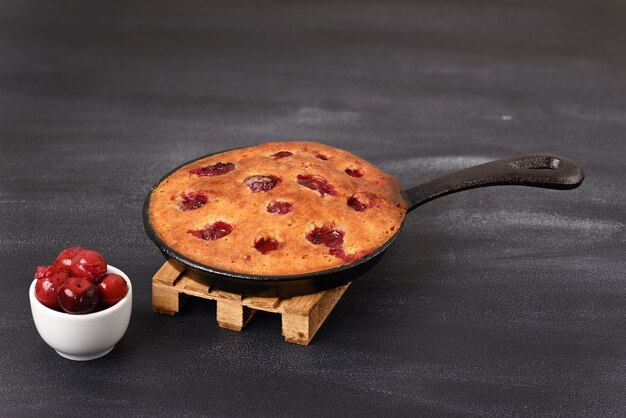 Sour cherry cake in a pan on a wooden trivet