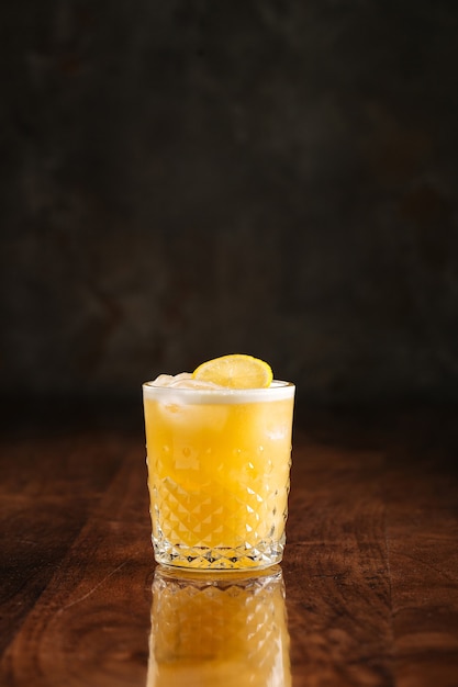 Sour cocktail on the wooden table with reflection