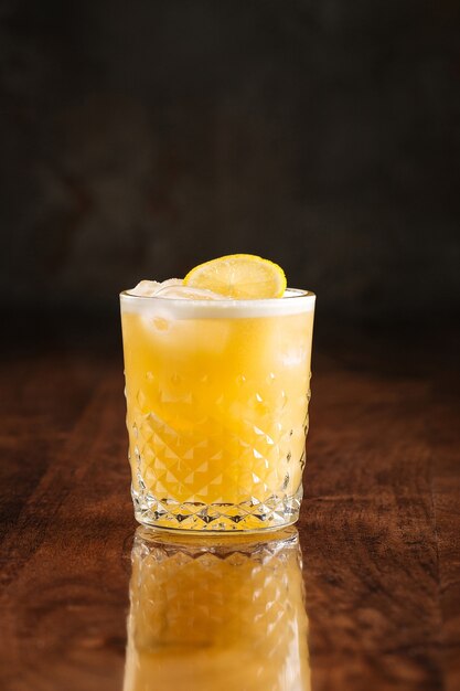 Sour cocktail on the wooden table with reflection