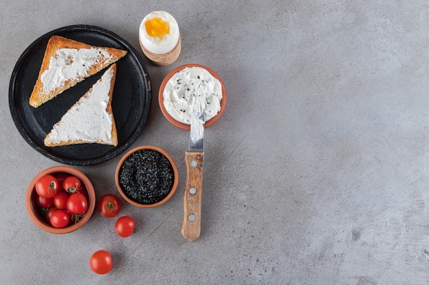 Sour cream, cherry tomatoes and toast bread on stone table.