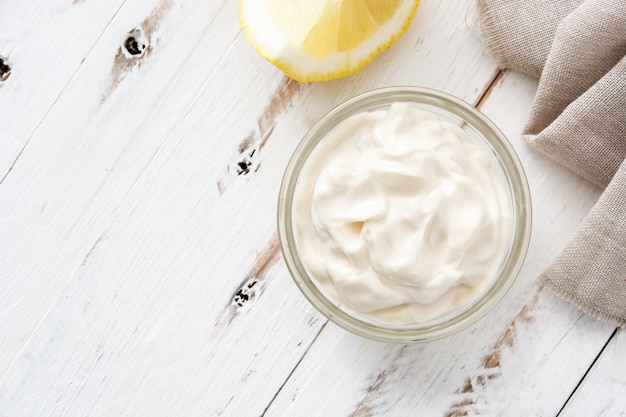 Sour cream in crystal bowl on white wood  