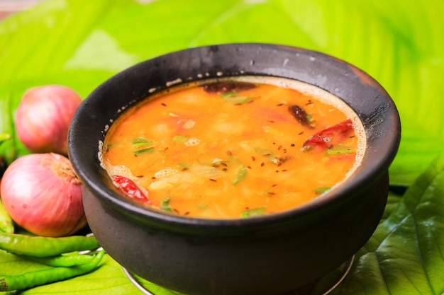 south indian famous rasamsambar served in a traditional mud pot closeup with selective focus and bl