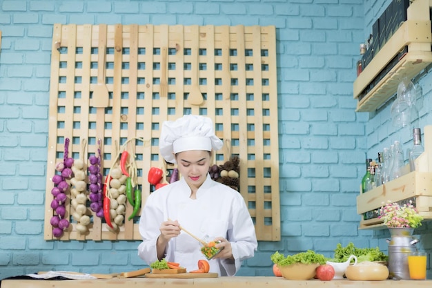 Southeast Asian female chef Thai She was wearing a white dress and hat She is cooking in the kitchen