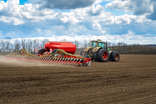 Sowing work in the field in spring. Tractor with seeder.