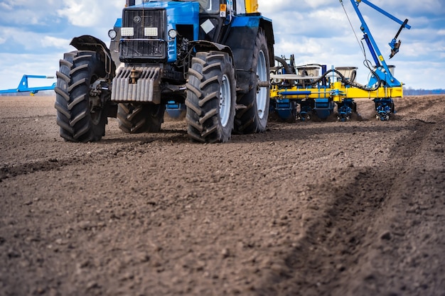 Sowing work in the field in spring. Tractor with seeder.