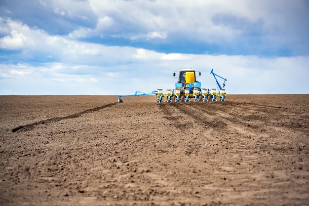 Sowing work in the field in spring. Tractor with seeder.