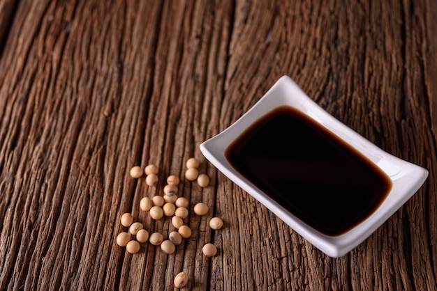 Soy Sauce with soy bean on wooden background.