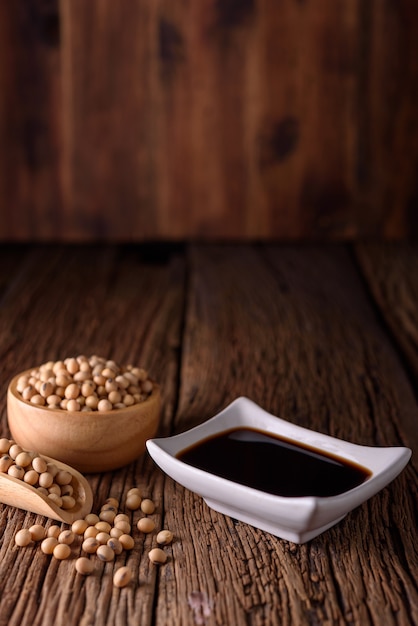 Soy Sauce with soy bean on wooden background.