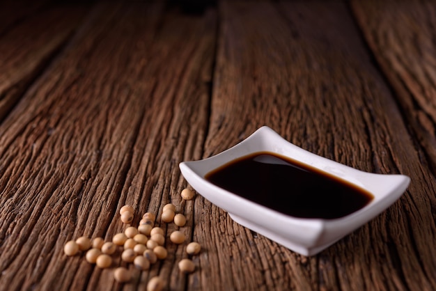 Soy Sauce with soy bean on wooden background.