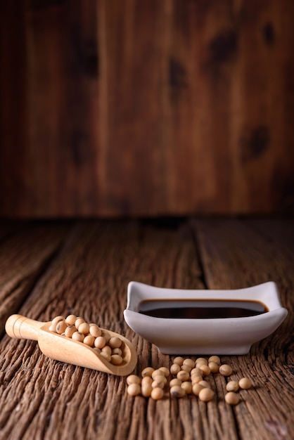 Soy Sauce with soy bean on wooden background.