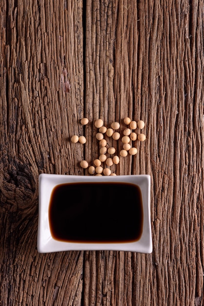 Soy Sauce with soy bean on wooden background.